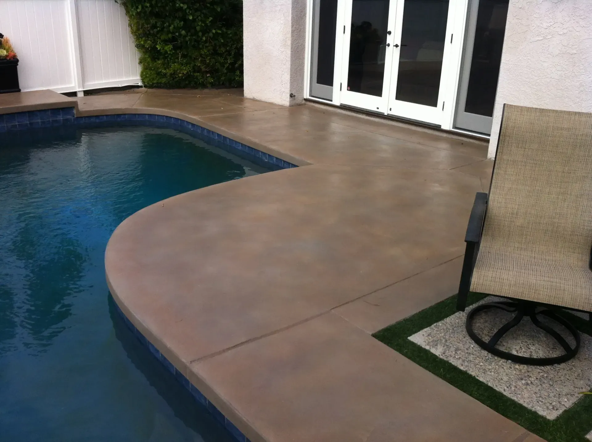A chair sits on a patio next to a swimming pool