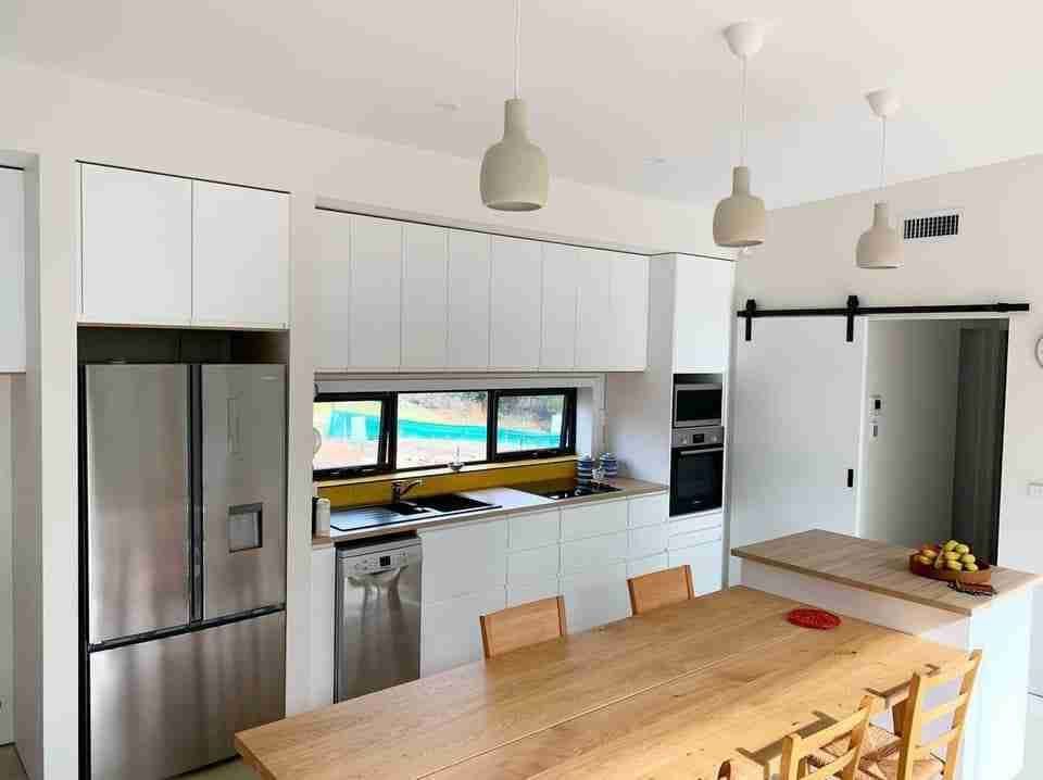 A Kitchen with White Cabinets, Stainless Steel Appliances, a Wooden Table and Chairs — Bay Coast Electrical & Control Solutions in Maloneys Beach, NSW