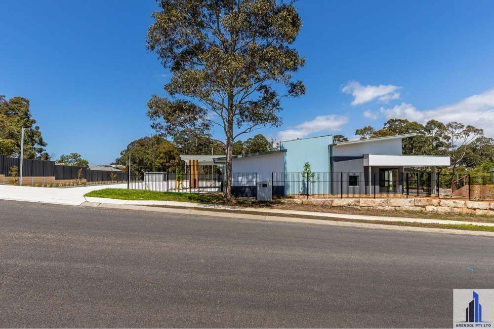 A Building With A Tree In Front Of It On A Sunny Day — BayCoast Electrical & Control Solutions in Maloneys Beach, NSW