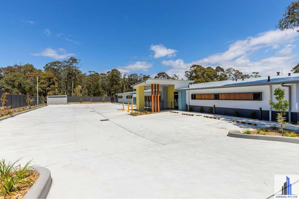 A Large Building With A Parking Lot In Front Of It — BayCoast Electrical & Control Solutions in Maloneys Beach, NSW