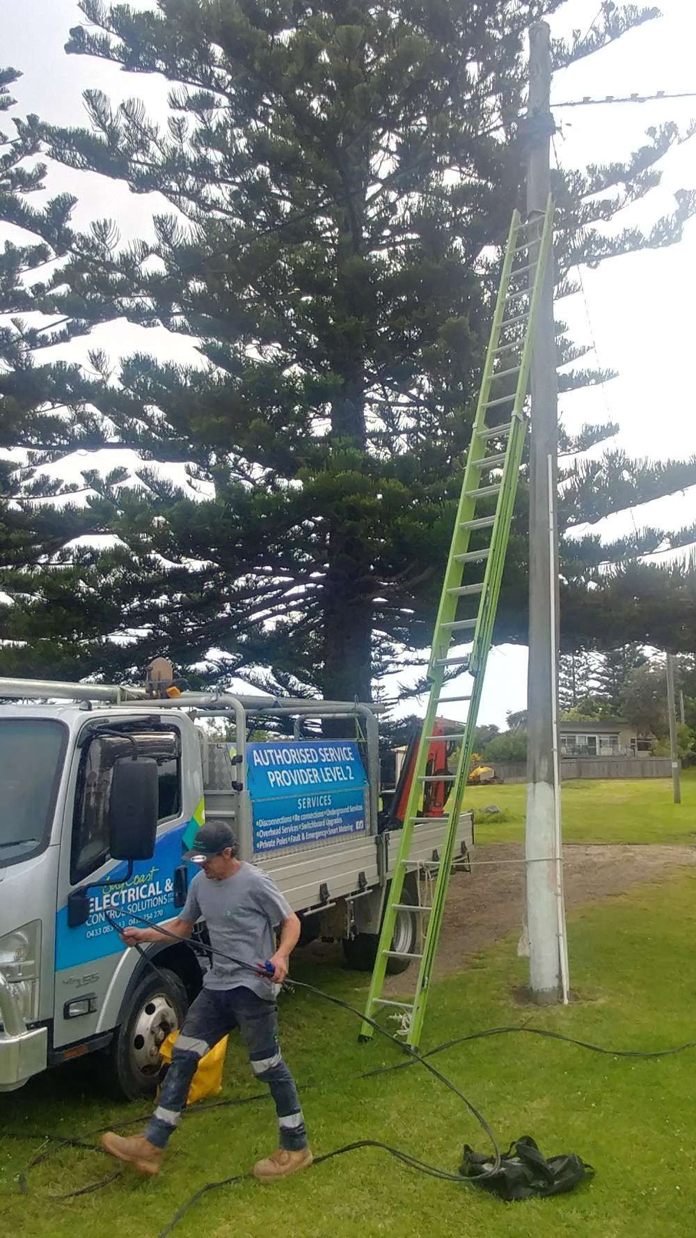 A Man Is Standing Next To A Truck With A Ladder Attached To It — BayCoast Electrical & Control Solutions in Maloneys Beach, NSW