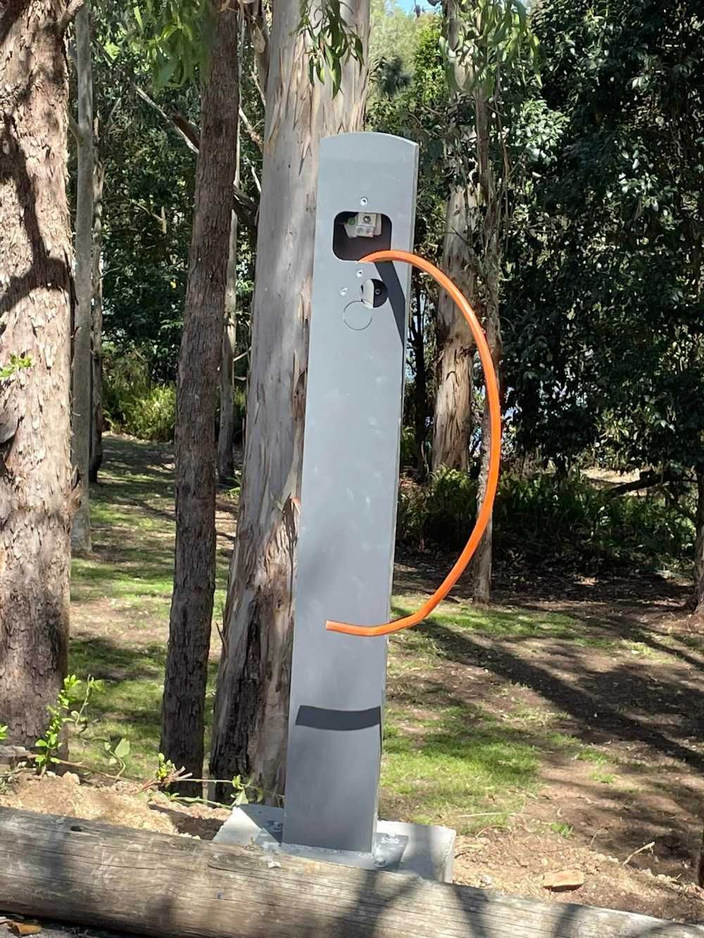 A Charging Station Is Sitting Next To A Tree In A Park — BayCoast Electrical & Control Solutions In South Durras, NSW
