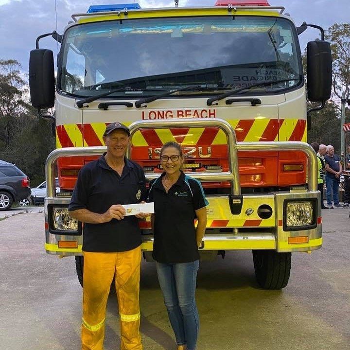 A Man And Woman Standing In Front Of A Long Beach Fire Truck — BayCoast Electrical & Control Solutions in Maloneys Beach, NSW
