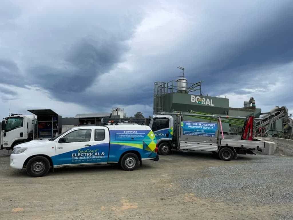 Two Trucks Are Parked Next to Each Other in Front of A Building — Bay Coast Electrical & Control Solutions in Maloneys Beach, NSW