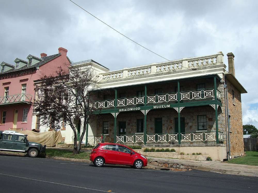 A Red Car Is Parked In Front Of A Large Building — BayCoast Electrical & Control Solutions in Braidwood, NSW