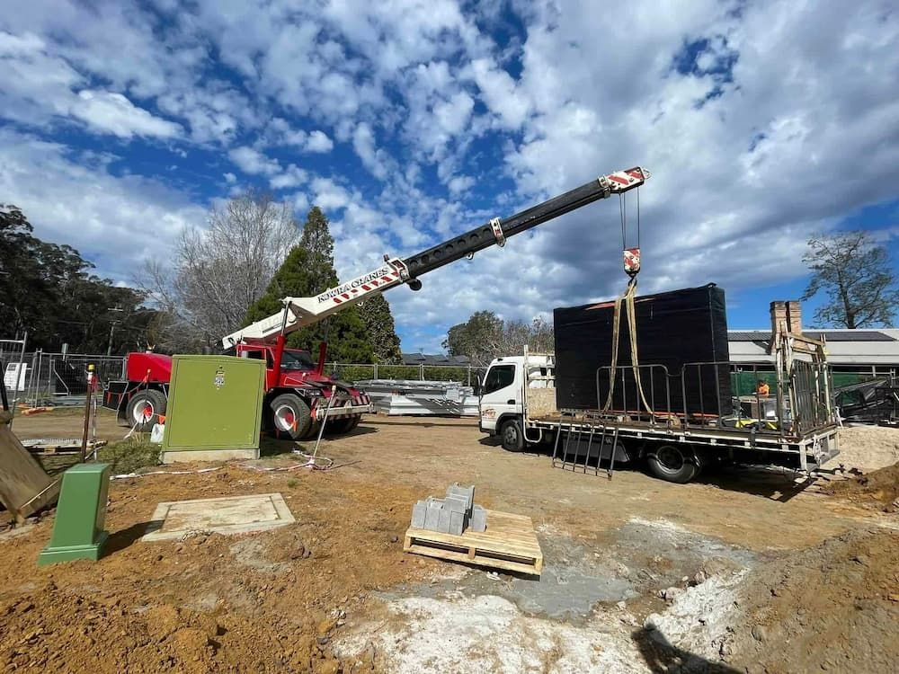 A Truck Is Being Lifted by A Crane on A Construction Site — Bay Coast Electrical & Control Solutions in Maloneys Beach, NSW