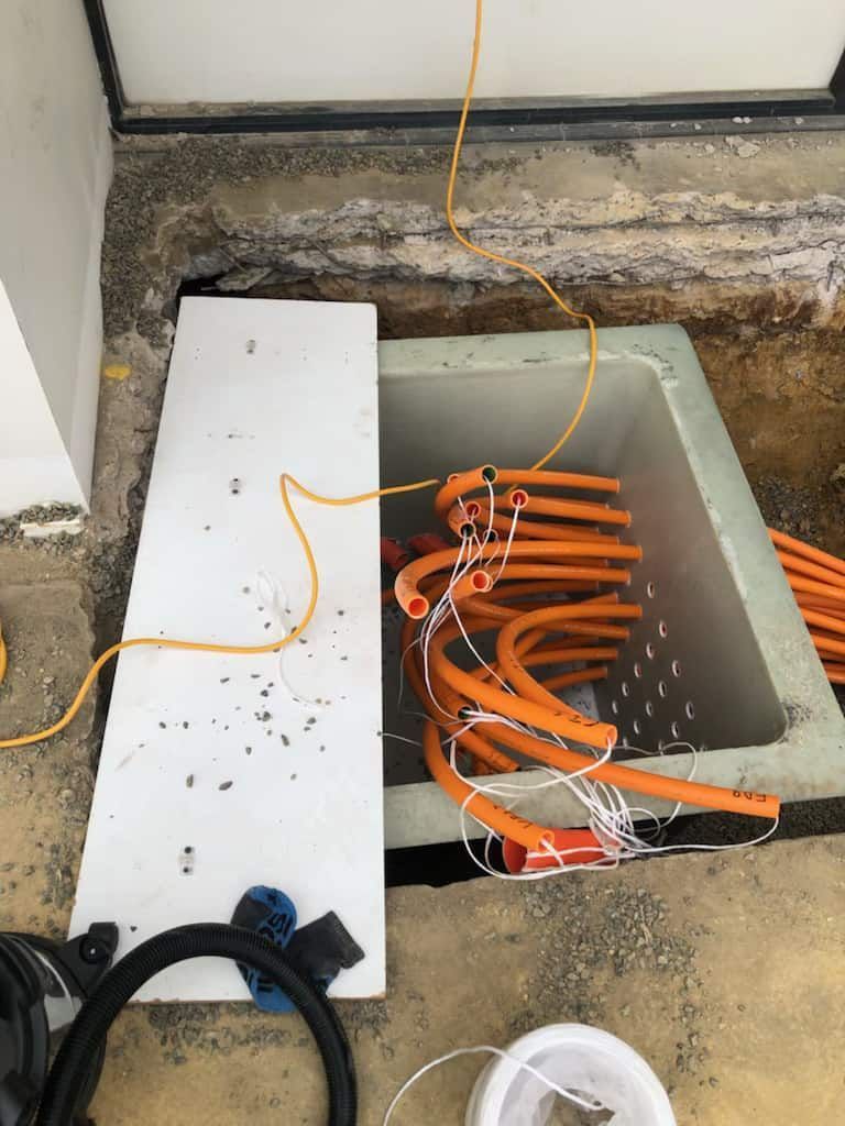 A Bunch of Orange Wires Are Coming out Of a Hole in The Ground — Bay Coast Electrical & Control Solutions in Maloneys Beach, NSW