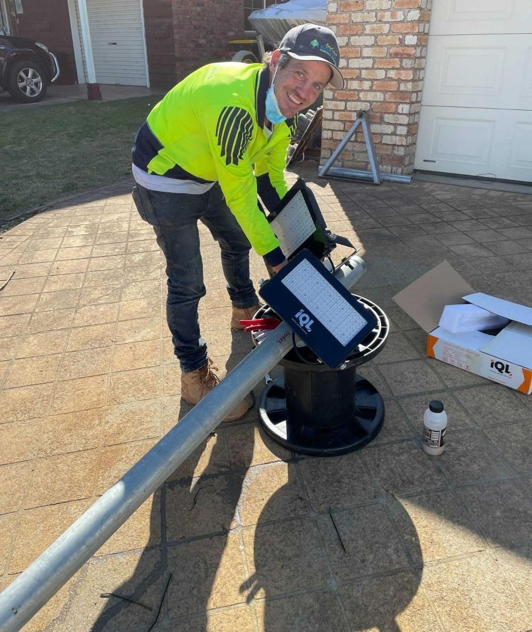 A Man Is Installing A Street Light On A Pole — BayCoast Electrical & Control Solutions in Maloneys Beach, NSW