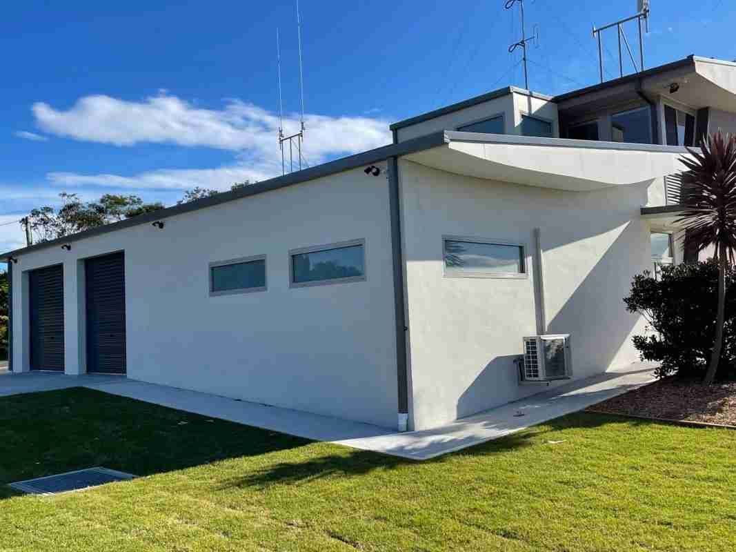 A White House with A Lot of Windows Is Sitting on Top of A Lush Green Lawn — Bay Coast Electrical & Control Solutions in Maloneys Beach, NSW