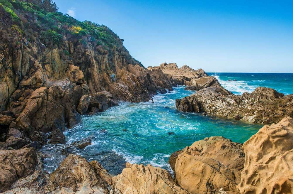 A Rocky Shoreline With A Body Of Water Surrounded By Rocks — BayCoast Electrical & Control Solutions in Moruya, NSW