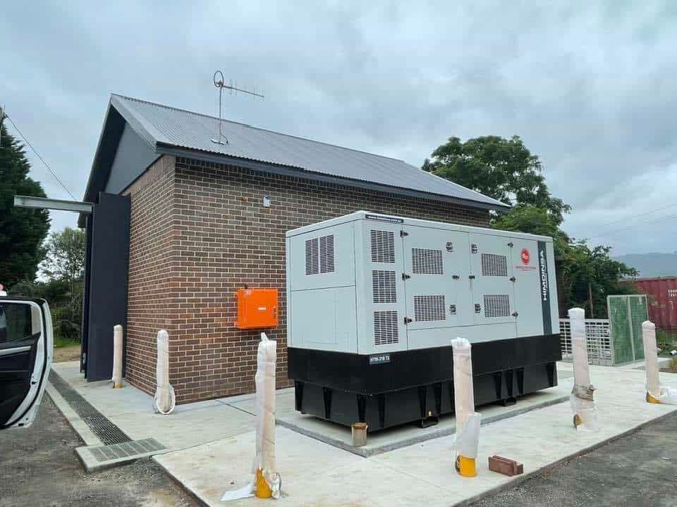 A Large Generator Is Sitting in Front of A Brick Building — Bay Coast Electrical & Control Solutions in Maloneys Beach, NSW