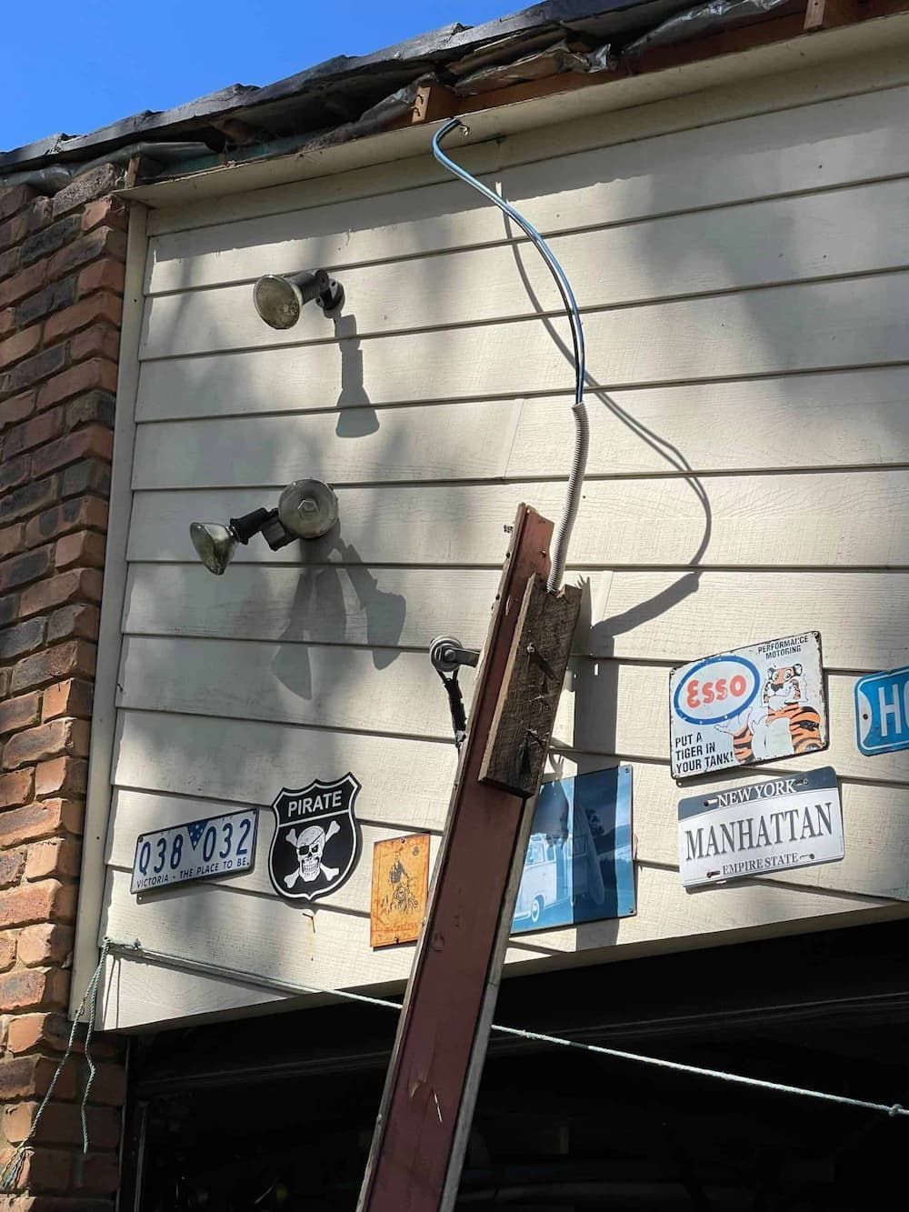 A Ladder Is Attached to The Side of A Garage with Stickers on It — Bay Coast Electrical & Control Solutions in Maloneys Beach, NSW