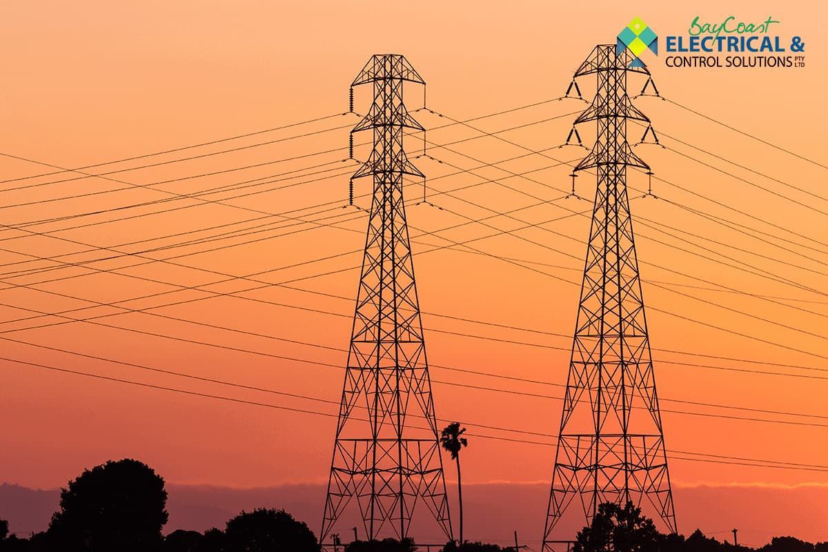 Two Electrical Towers Are Silhouetted Against a Sunset Sky — Bay Coast Electrical & Control Solutions in Maloneys Beach, NSW