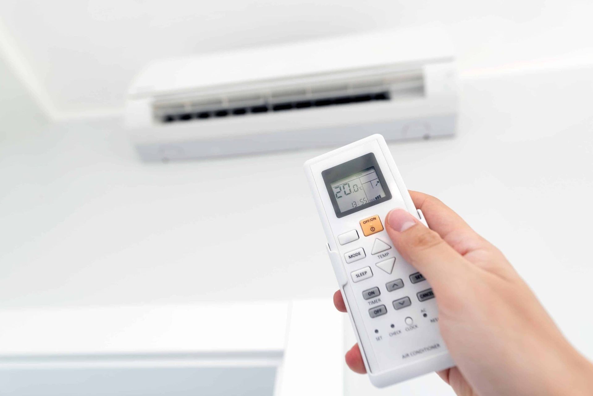 A Person Is Holding a Remote Control in Front of An Air Conditioner — Bay Coast Electrical & Control Solutions in Maloneys Beach, NSW