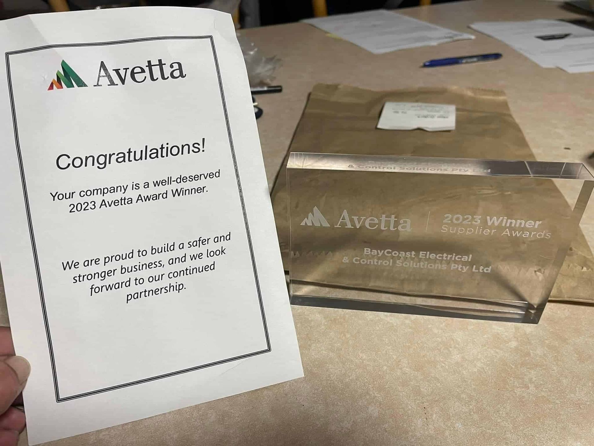 A Person Is Holding A Piece Of Paper That Says Congratulations — BayCoast Electrical & Control Solutions in Maloneys Beach, NSW