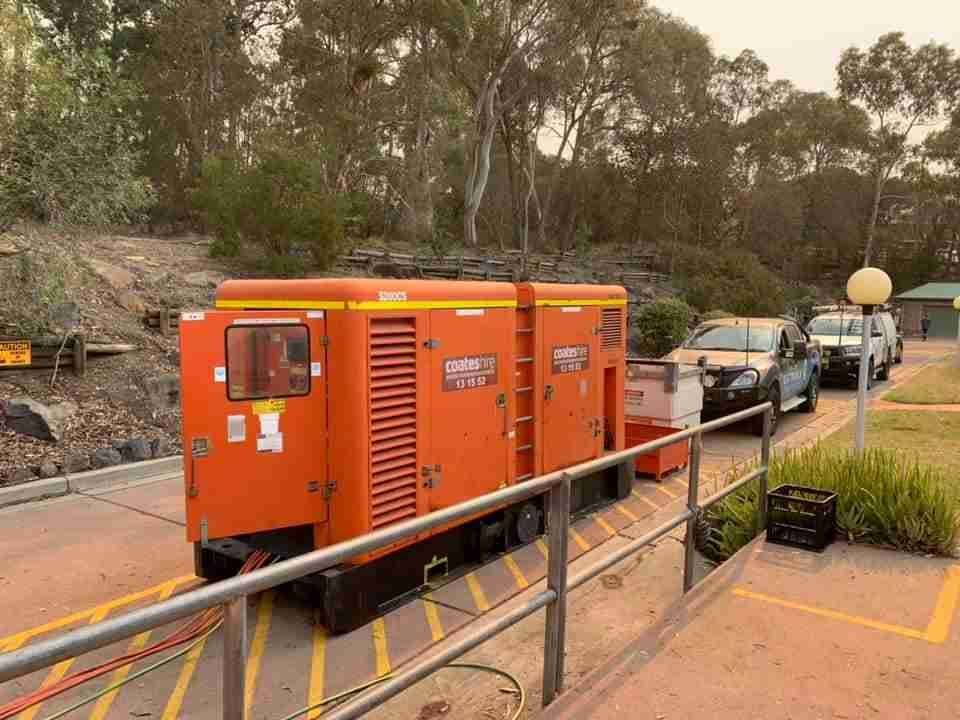 A Large Orange Vehicle Is Parked in A Parking Lot Next to A Railing — Bay Coast Electrical & Control Solutions in Maloneys Beach, NSW