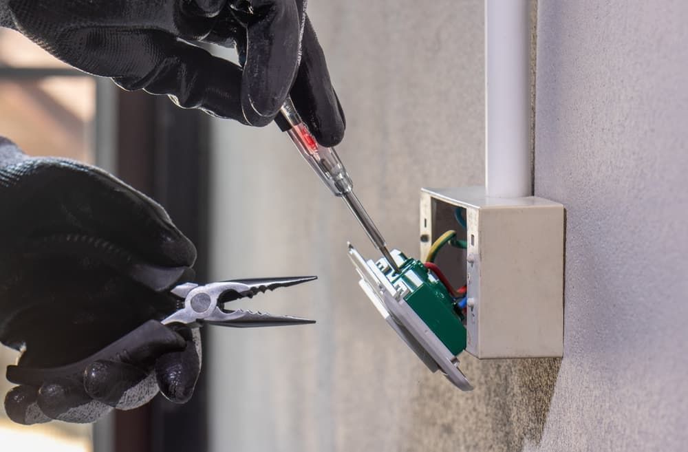A Person Is Using a Screwdriver to Fix a Light Switch — Bay Coast Electrical & Control Solutions in Maloneys Beach, NSW