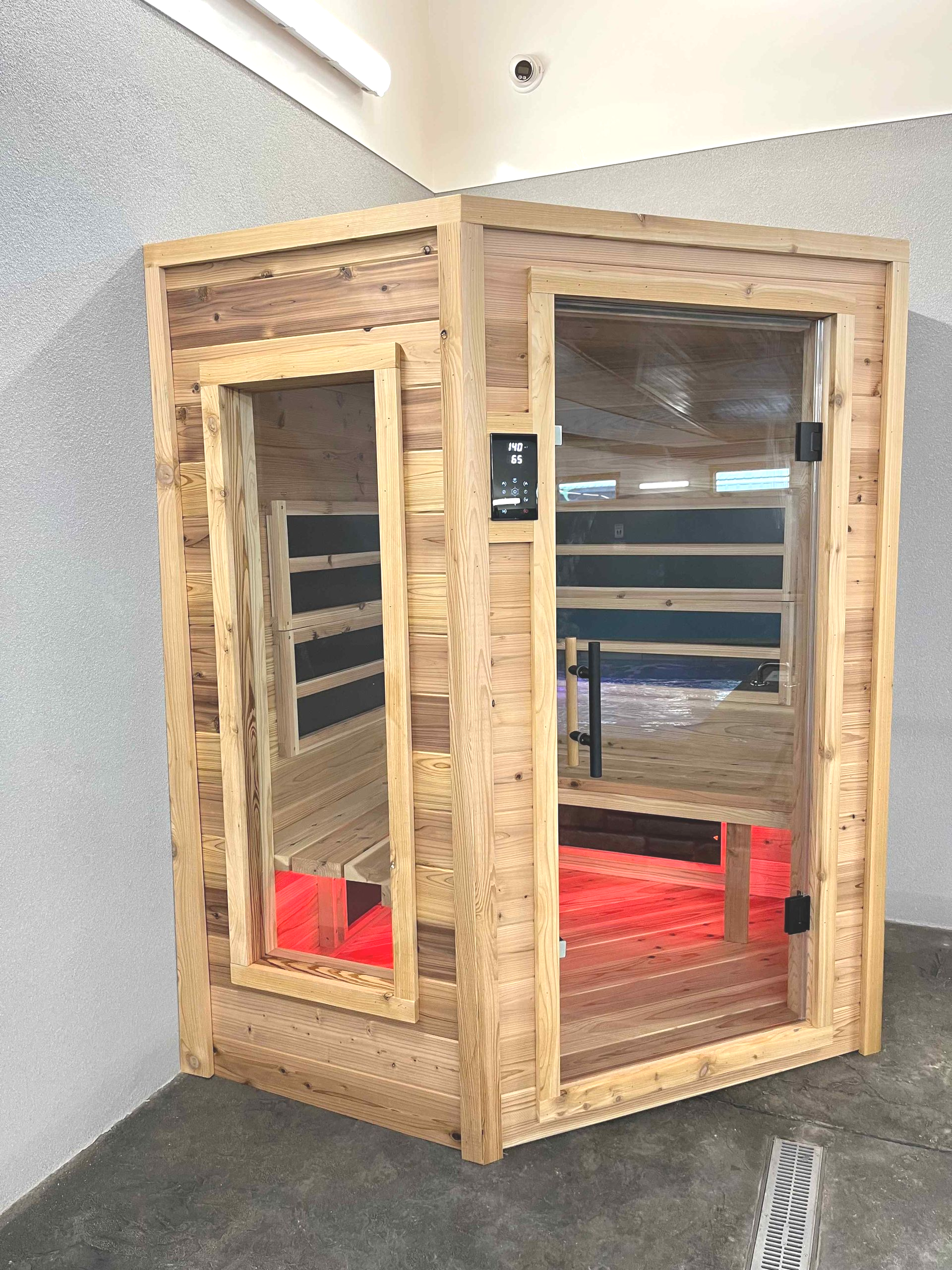 Wooden corner infrared sauna with glass door and side window.