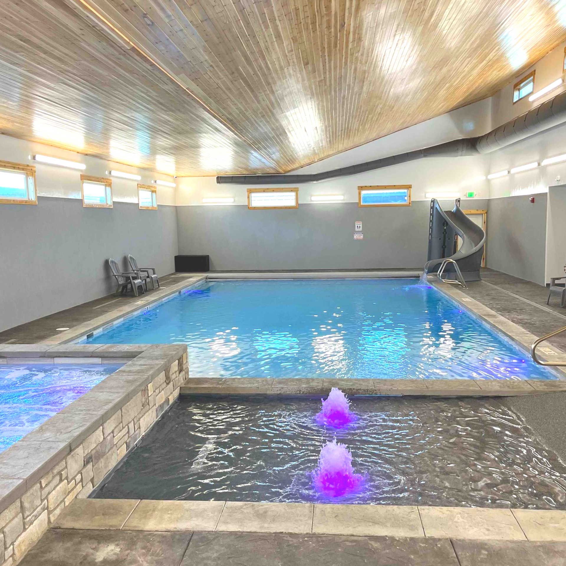 Indoor pool with a water slide, fountains, and hot tub.