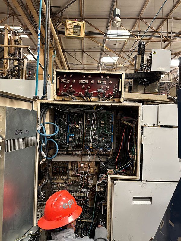 Un hombre con casco está trabajando en una máquina en una fábrica.