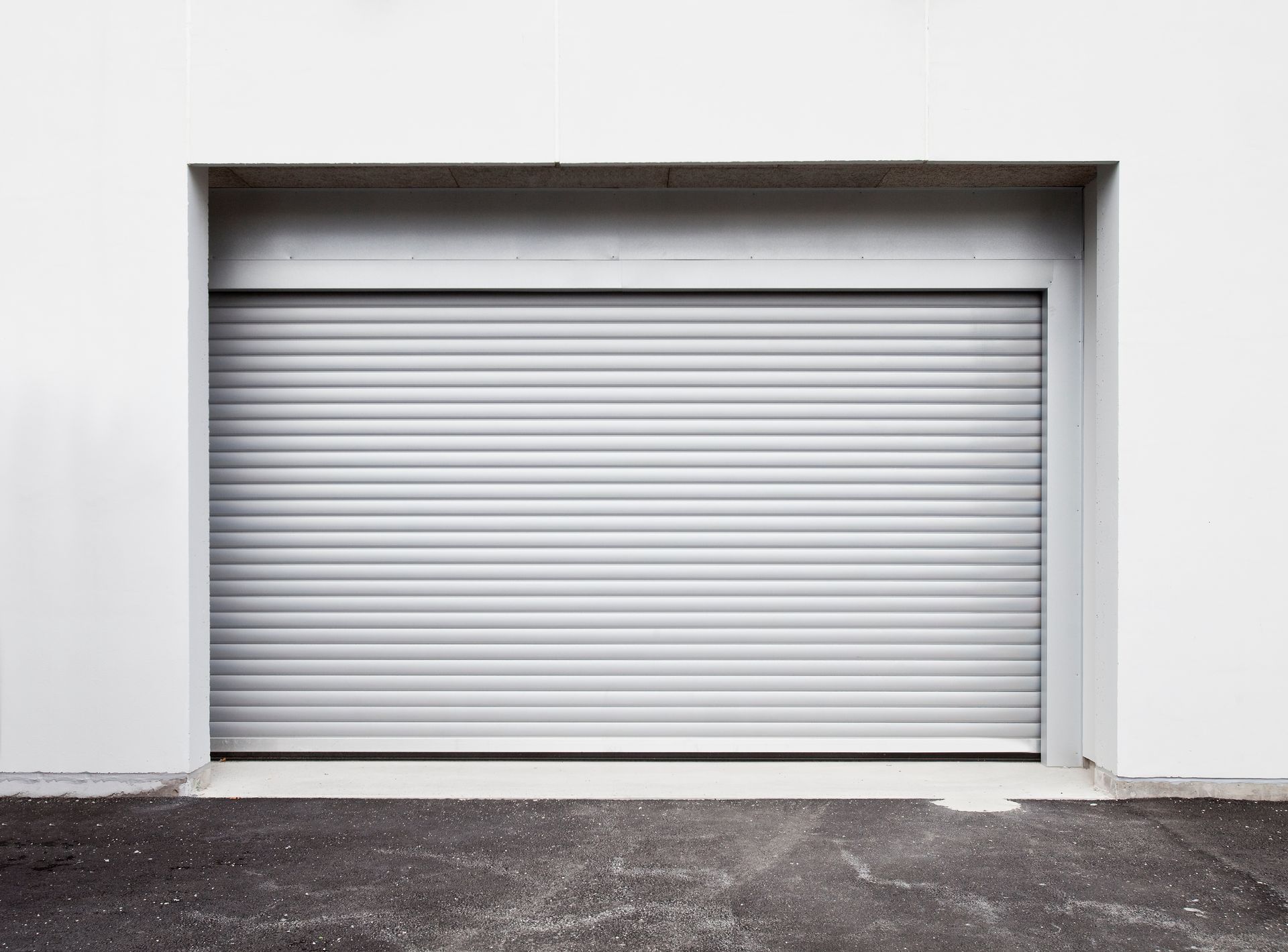 Closed gray roll-up garage door in a white wall opening