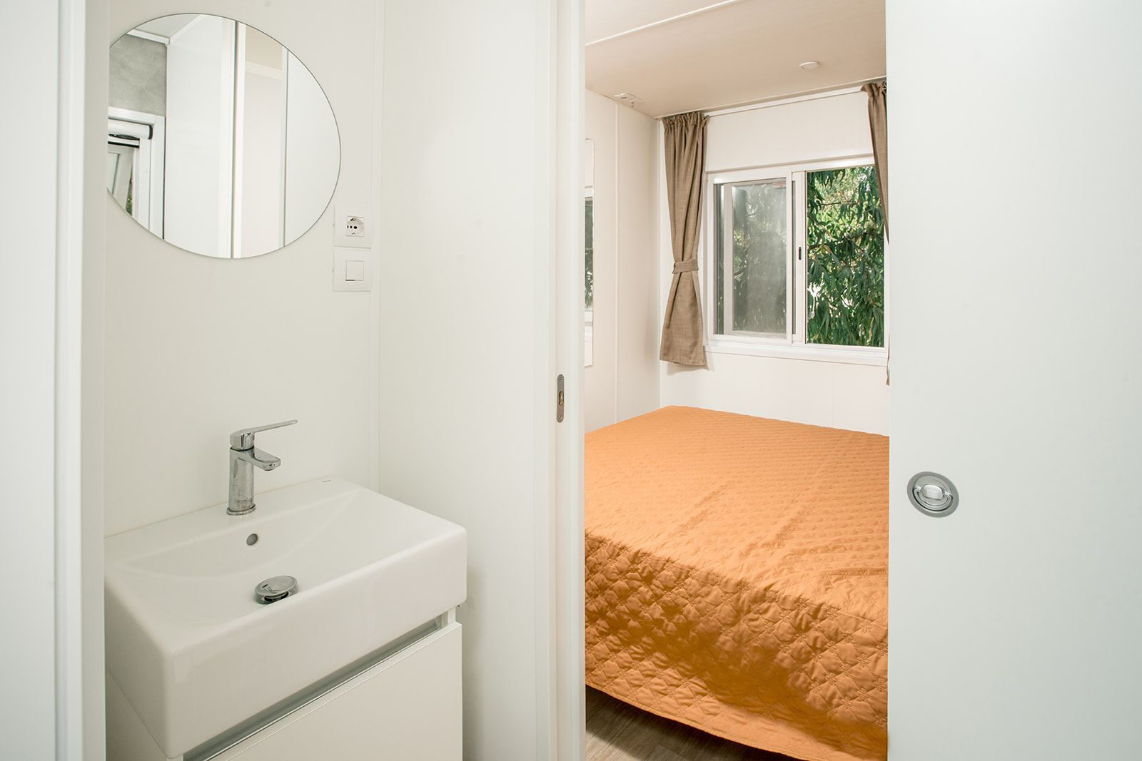 Lo chef in camice bianco e grembiule a righe sorride, seduto fuori.