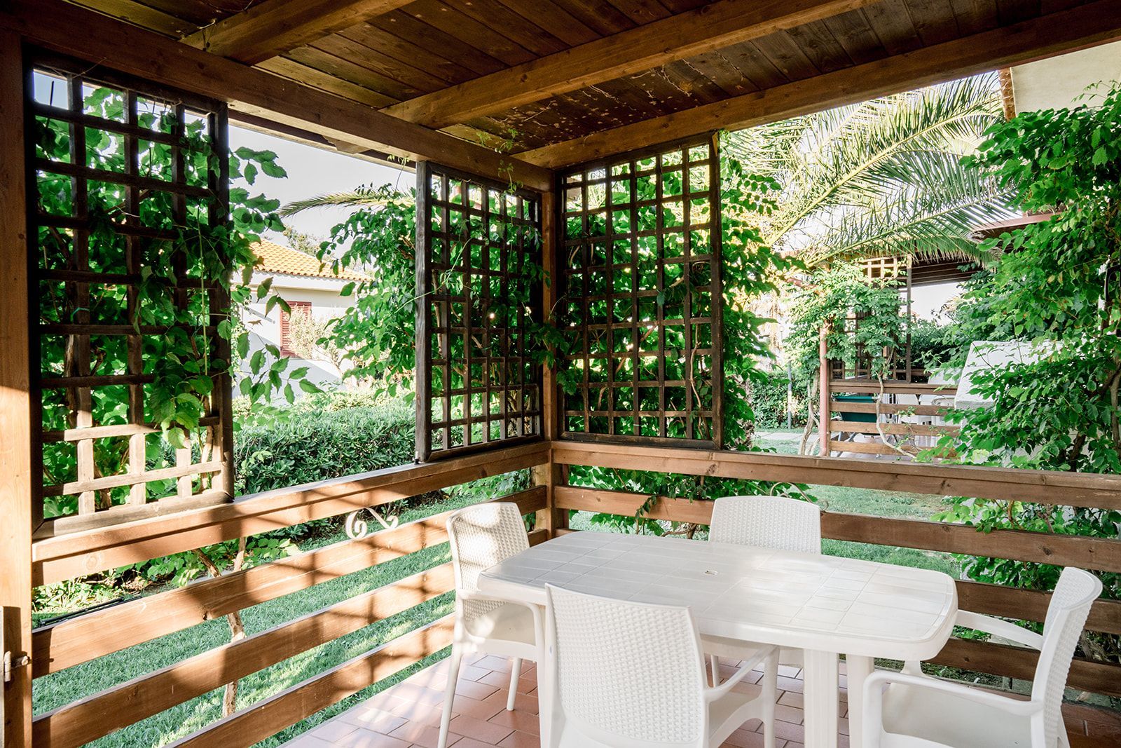 Lo chef in camice bianco e grembiule a righe sorride, seduto fuori.