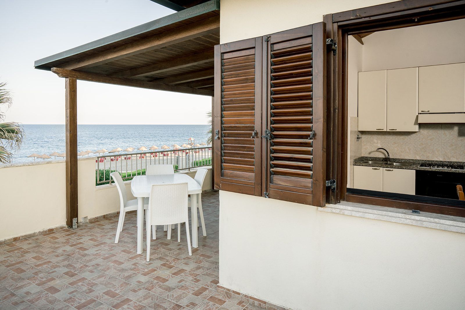 Lo chef in camice bianco e grembiule a righe sorride, seduto fuori.