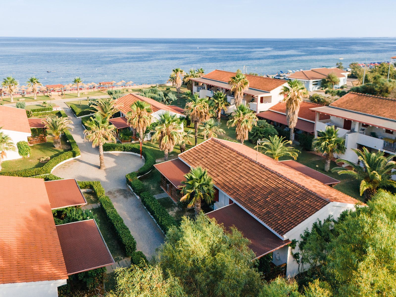 Lo chef in camice bianco e grembiule a righe sorride, seduto fuori.