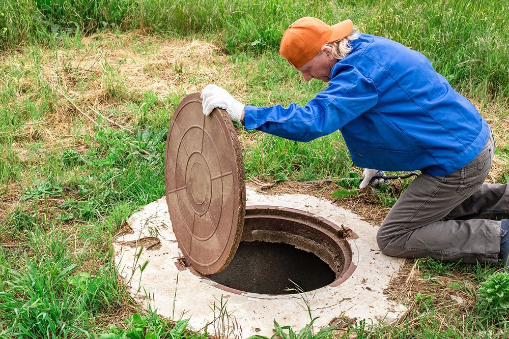 The man opened the cover of the sewer manhole for Inspection.