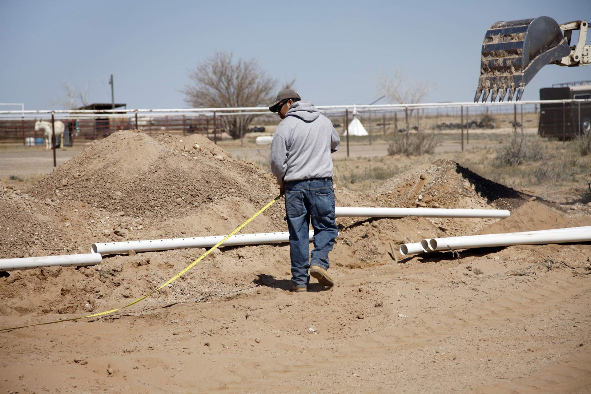Worker measuring ground near septic pipe installation. Worker measuring ground near septic pipe installation.