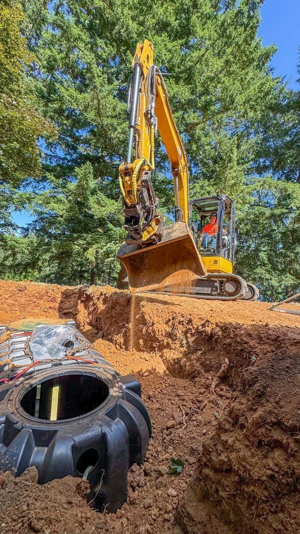 A machine pouring sand into a hole, illustrating the septic tank system installation procedure.
