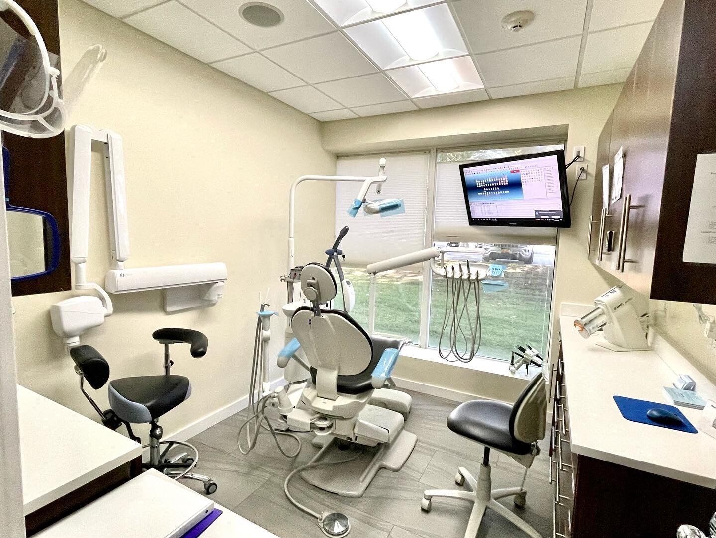 Dental office examination room with dental chair, equipment, window.