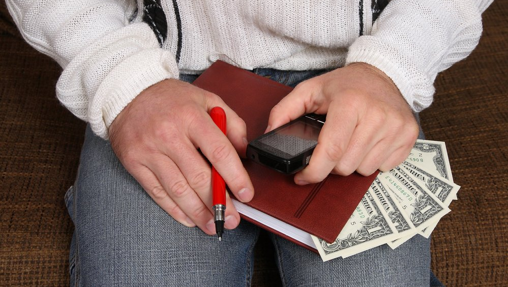 Man holding a notebook with money, calculator and pen while getting a divorce