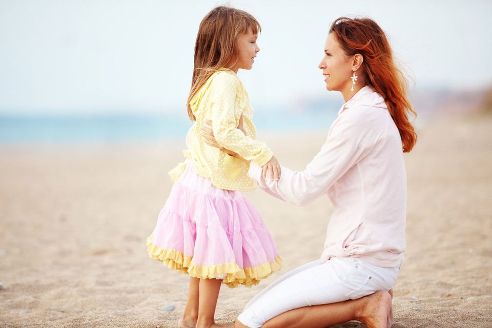 Mother talking to her daughter on the beach about divorce