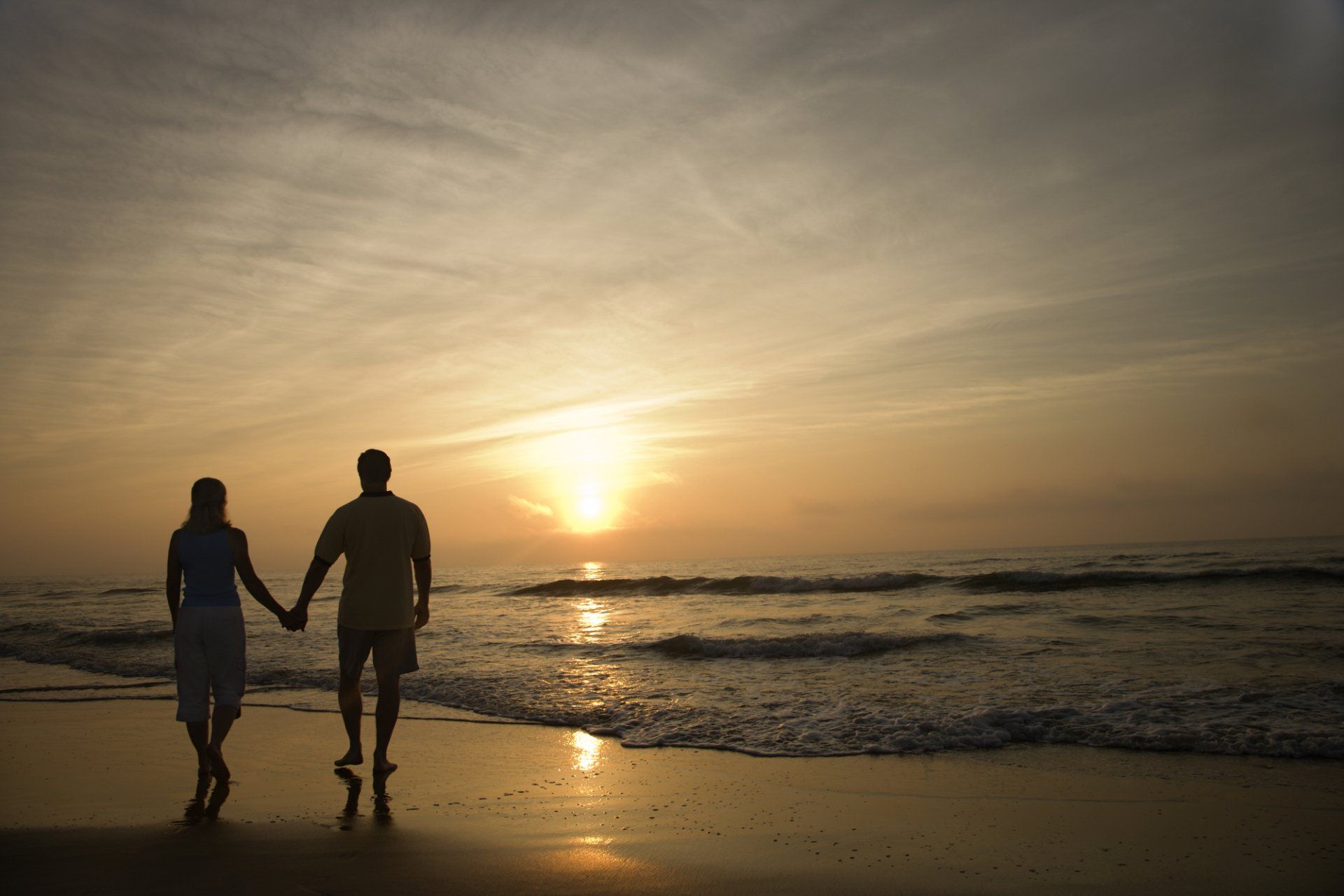 couple walking along a beach at sunset