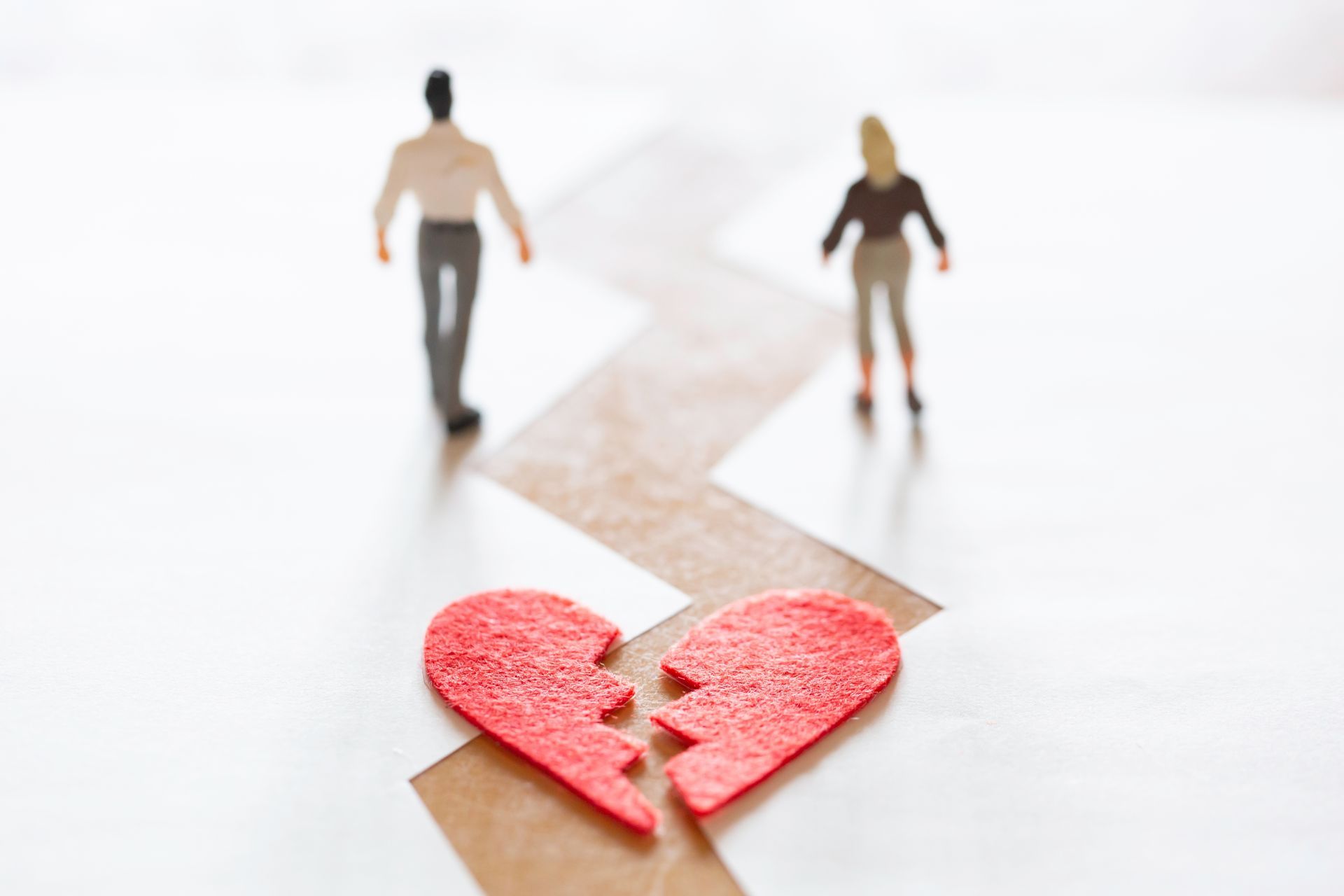 Broken red heart with two small figures walking apart on a white background
