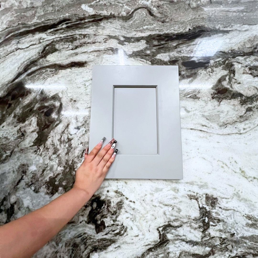 A person is touching a cabinet door on a marble counter top.
