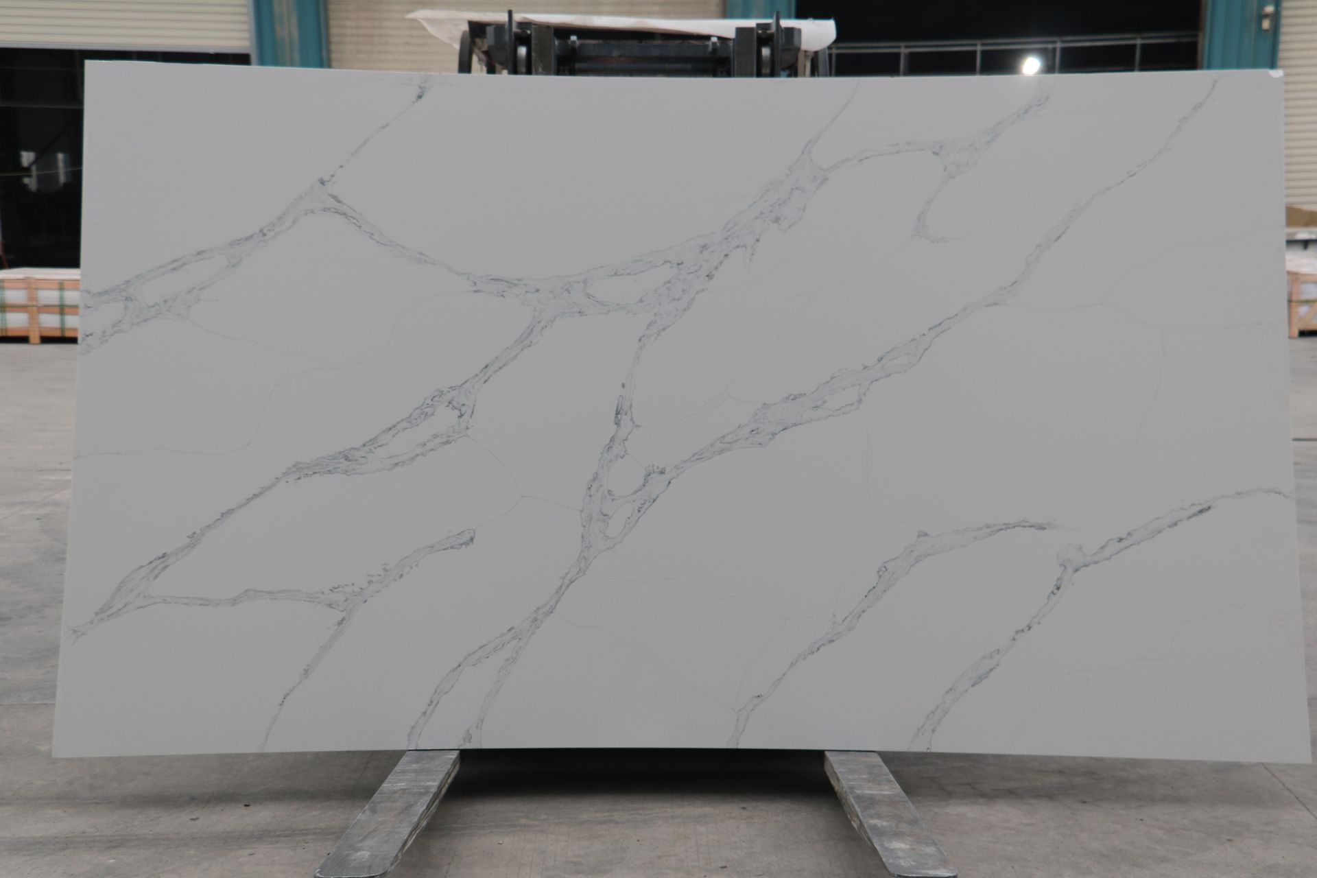A large white marble slab is sitting on top of a forklift in a warehouse.