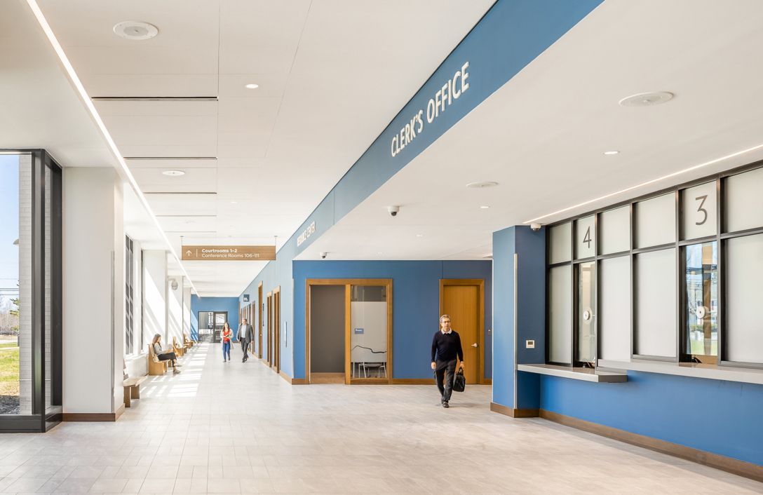 A woman is walking down a long hallway in a building.