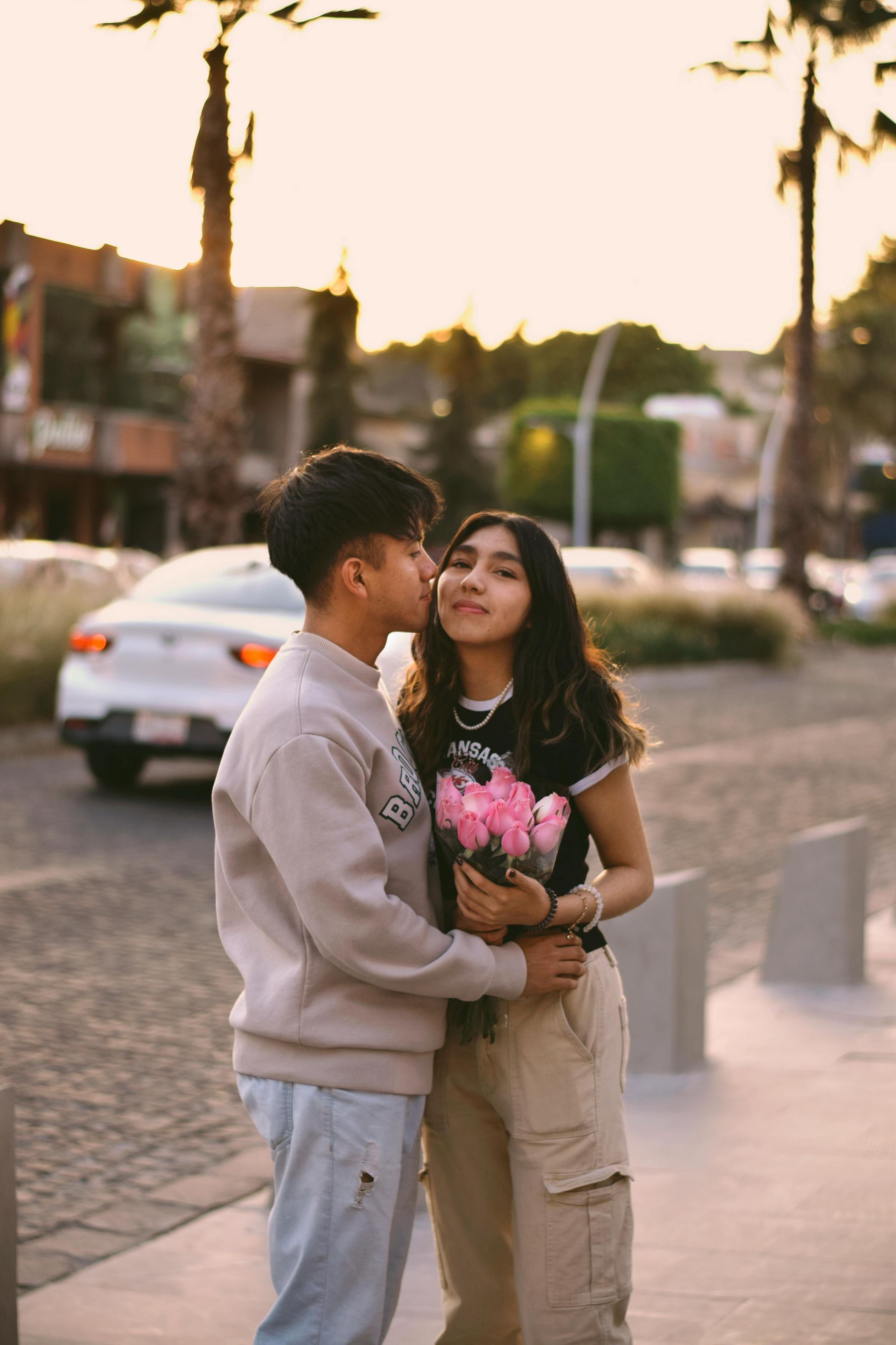 A man is kissing a woman on the cheek while holding a bouquet of flowers.