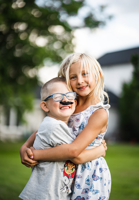 A boy and a girl are hugging each other in a park.