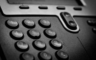 Close-up of a black office phone keypad with numbered buttons, including asterisk and pound symbols.