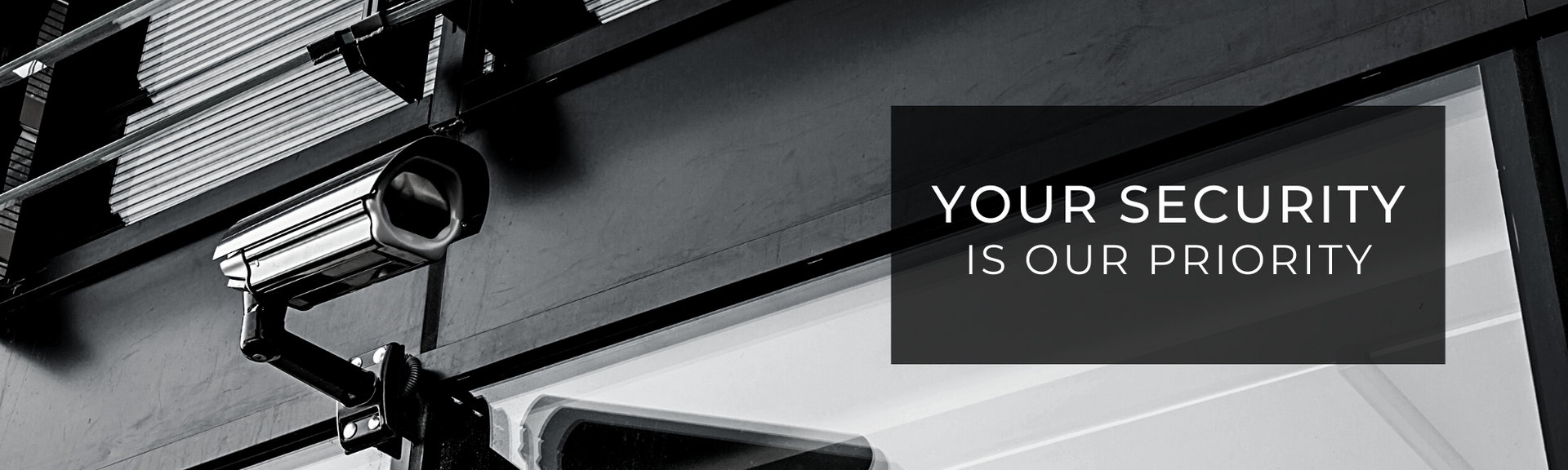 A black-and-white image of a security camera mounted on a wall, with the text 