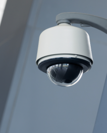 A white dome security camera mounted on a wall against a grey background.