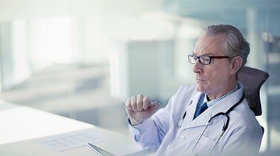 a doctor is sitting at a desk in front of a laptop computer .