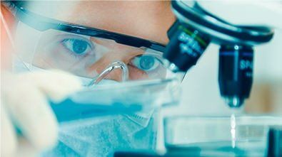 a scientist is looking through a microscope in a laboratory .