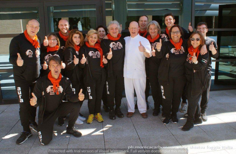Un gruppo di persone posa per una foto e una di loro indossa una maglietta con la scritta
