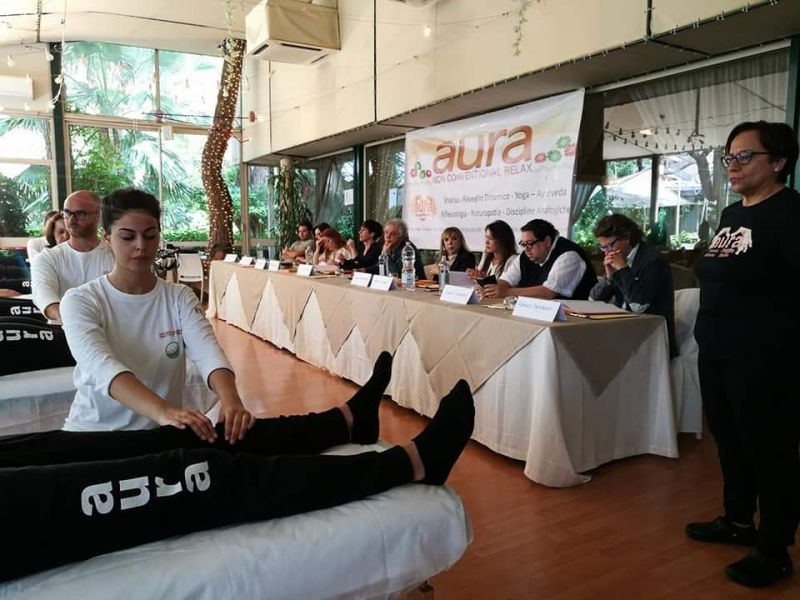 Un gruppo di persone è seduto a un tavolo con un cartello che dice aura.