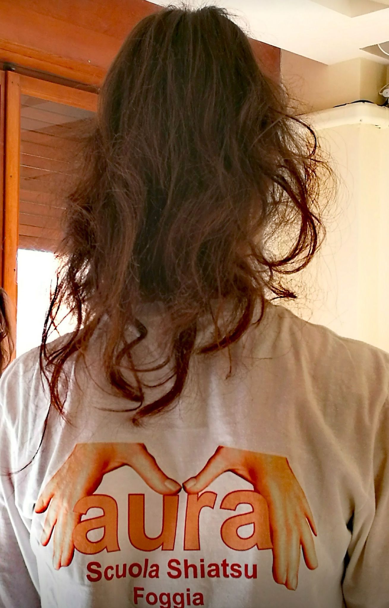 Una donna che indossa una maglietta con la scritta aura scuola shiatsu foggia